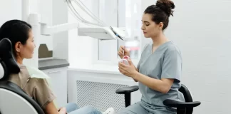Dentystka wyjaśnia dorosłej pacjentce zabieg, trzymając model szczęki.